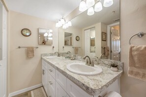 A bathroom with two sinks, a large mirror, and a clock on the wall. - Roseates Retreat Condo: Sleeps 6 with an amazing view (Cedar Key)