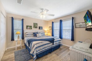 A bedroom with a bed, a ceiling fan, a TV, and a small table. - Roseates Retreat Condo: Sleeps 6 with an amazing view (Cedar Key)