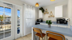 A modern kitchen with a central island, white cabinetry, and a view through large windows. - Daisy House: Downtown Cedar Key.  Walk to everything! (Cedar Key)