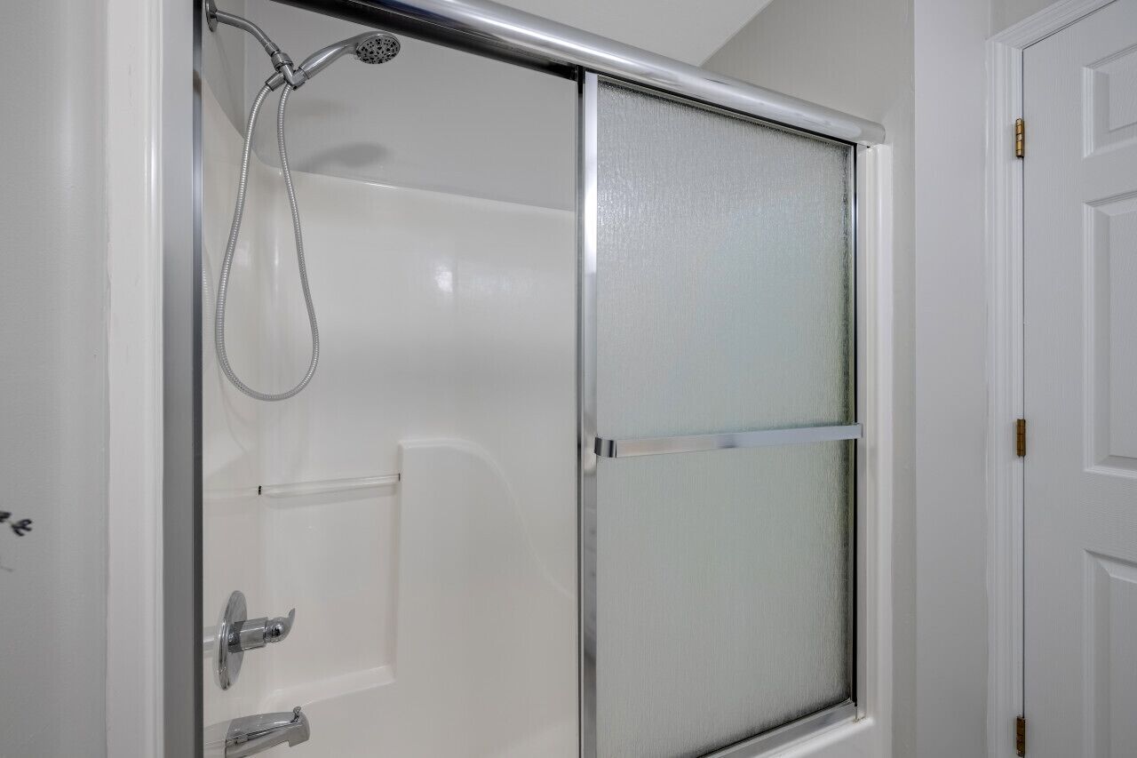A shower enclosure with a glass door and a showerhead.