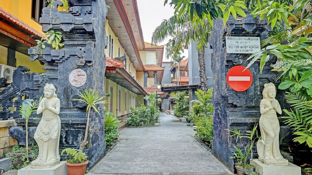 A pathway flanked by statues and a sign indicating a security checkpoint. - Collection O 91081 New Arena Hotel (Kuta)