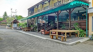 A restaurant with outdoor seating, a covered patio, and a staircase leading to an upper level. - Collection O 91081 New Arena Hotel (Kuta)