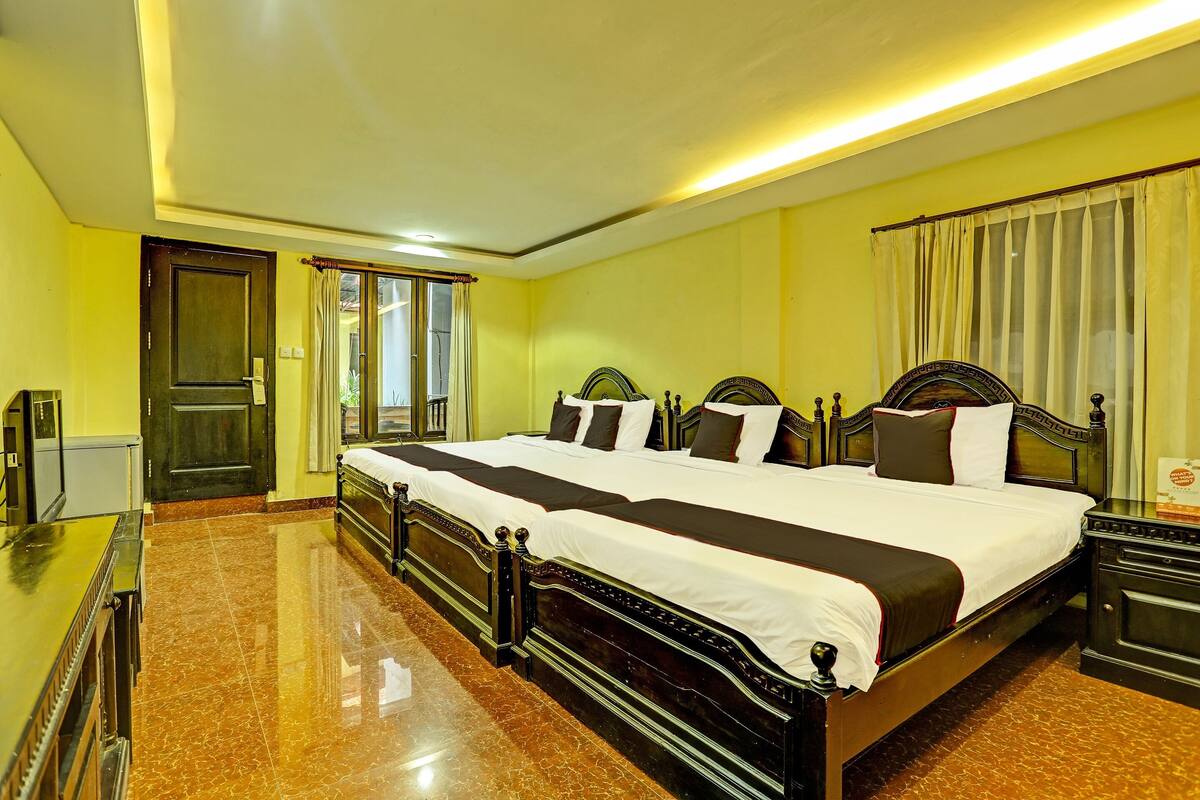 A hotel room with a large bed, a desk, and a wardrobe.