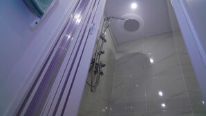 Ein Badezimmer mit Dusche, gefliesten Wänden und einer Deckenleuchte.