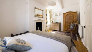 Una camera da letto con un letto, una cassettiera, una sedia e uno specchio appeso al muro.