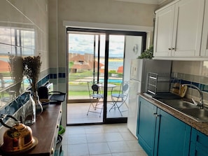 A kitchen with a view of a pool and buildings, a sliding glass door, and a dining area with chairs.