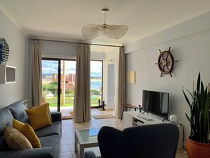 Un salon avec un canapé, une table basse, un téléviseur et une plante en pot.