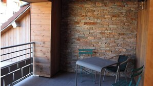 A wooden balcony with a stone wall, a metal railing, and two green chairs. - Grand Appartement Avec Loggia (Orchamps-Vennes)