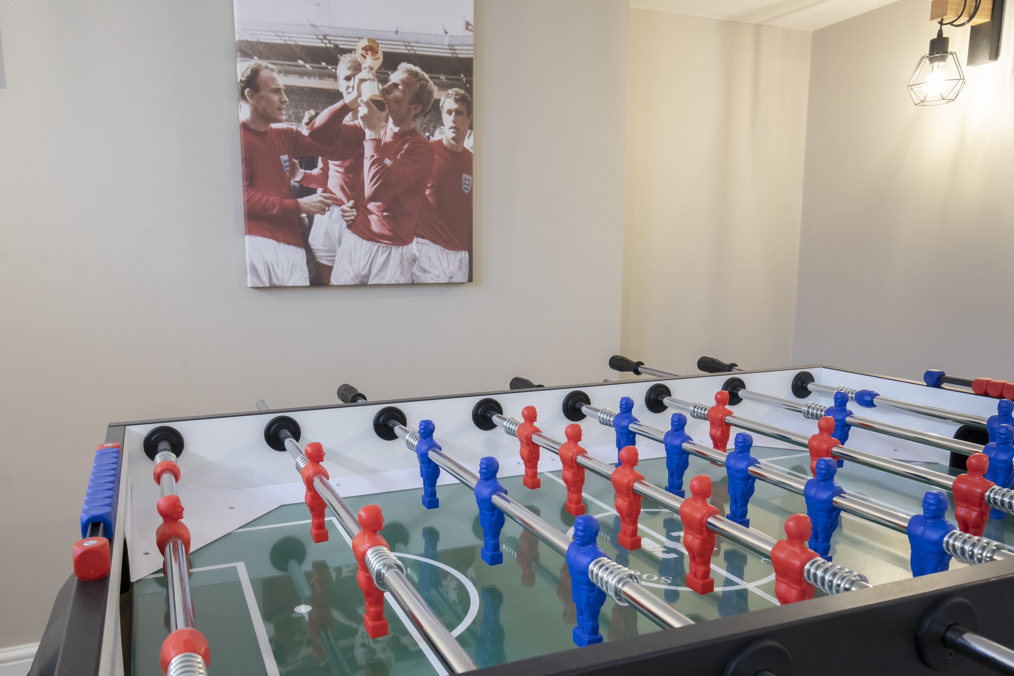 Une table de baby-foot dans une pièce où est accrochée une photo encadrée au mur.