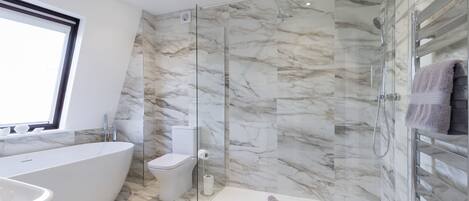 A modern bathroom with a glass-enclosed shower, a freestanding bathtub, and a toilet.