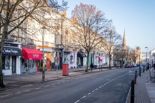 A street lined with shops, including a restaurant with a red awning.