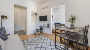 Een moderne woonkamer met een bank, een salontafel, en een eethoek met een tafel en stoelen.