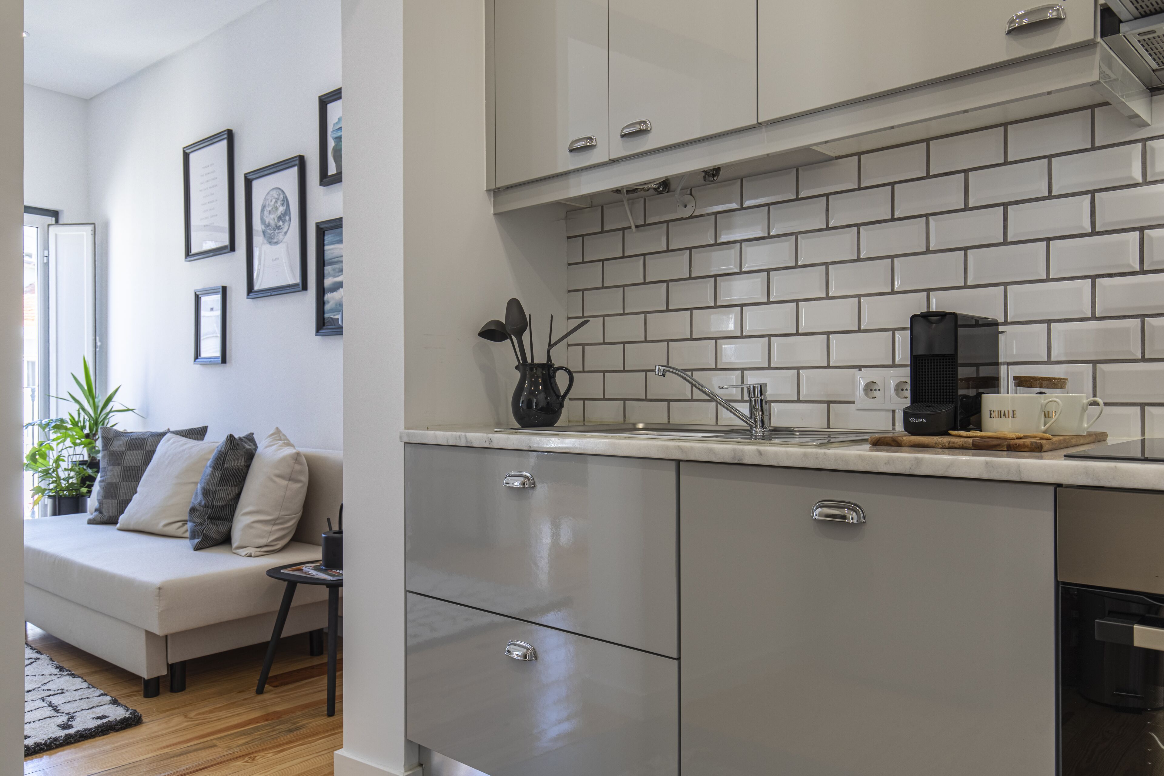 A modern kitchen with grey cabinets, a tiled backsplash, and a coffee machine.
