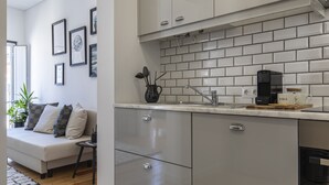 Een moderne keuken met grijze kastjes, een betegelde spatwand en een koffieapparaat.