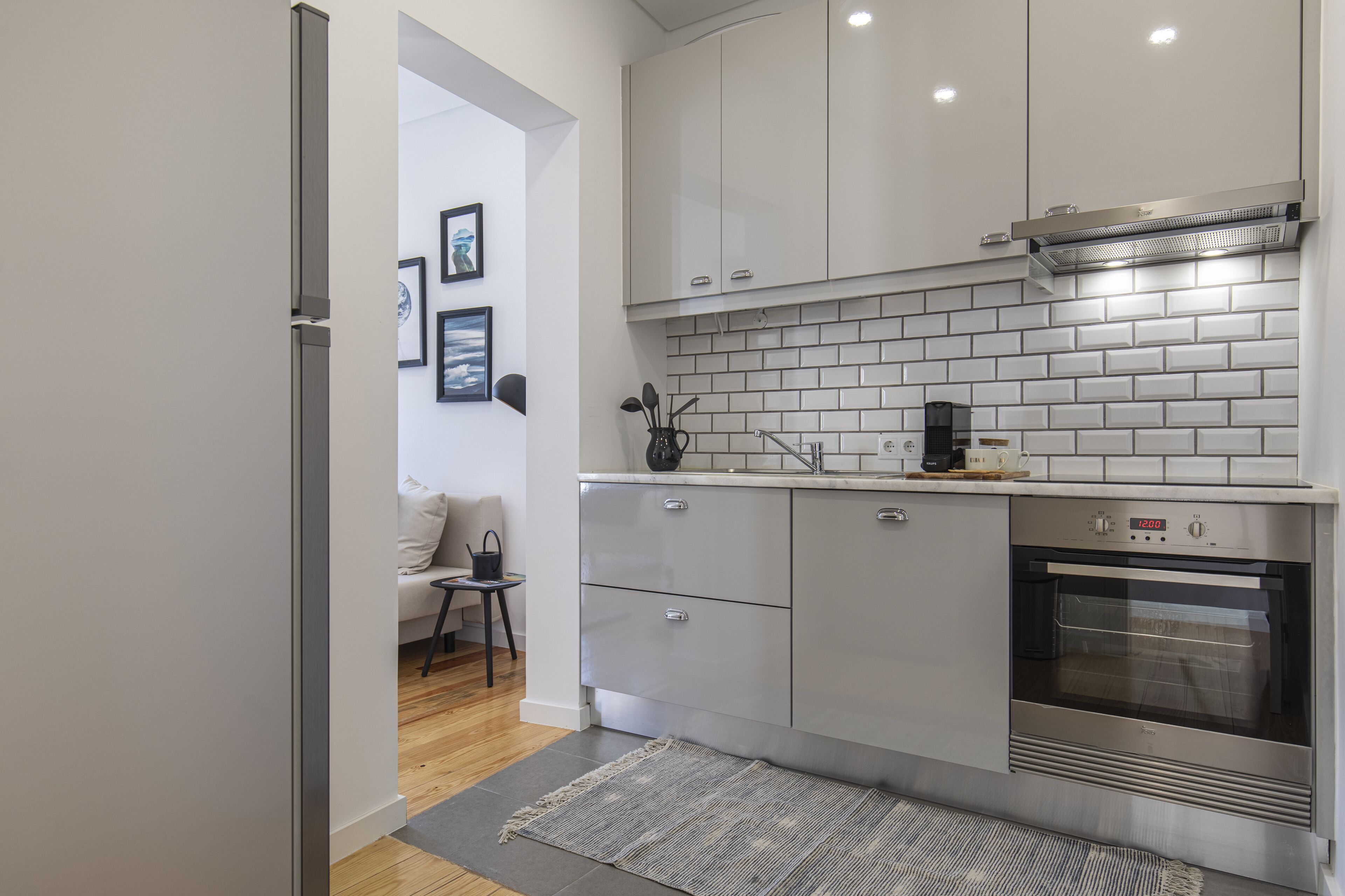 A modern kitchen with white cabinets, a built-in oven, and a coffee maker on the countertop.