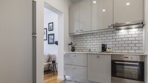 Een moderne keuken met witte kasten, een inbouwoven en een koffiezetapparaat op het aanrecht.