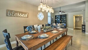 A dining area with a wooden table set for four, a chandelier, and a 'blessed' sign on the wall. - Near Golf! Snowbird Poolside Escape in Scottsdale (Scottsdale)