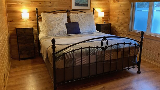 A wooden-paneled room with a metal-framed bed, two bedside tables, and a window. - Cozy Suite 15 min away from Mt Tremblant. Pet Friendly (Mont-Tremblant)