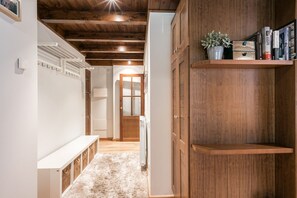 Un corridoio con travi in legno, una panca bianca, un termosifone e una libreria con libri e una pianta.
