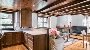 Una cocina moderna con armarios de madera y una isla grande, una zona de estar acogedora con chimenea y televisor.