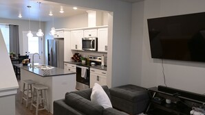 A modern kitchen with white cabinets, stainless steel appliances, and pendant lighting. - Cozy townhome (Billings)