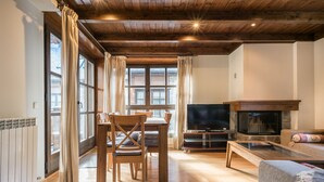 A cozy living room with a wooden ceiling, a fireplace, a TV, and a dining area with a table and chairs. - Tulmas by Totiaran em Baqueira 2 dorm. 2 baños a pie de pistas (Baqueira)