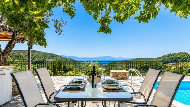 Mesa para cuatro con vista a un paisaje montañoso y una piscina.