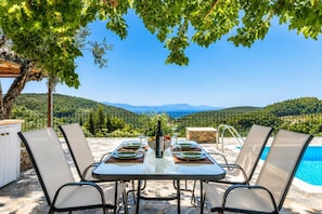 Mesa para cuatro con vista a un paisaje montañoso y una piscina.