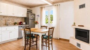 Una cocina con armarios de madera, una mesa de comedor con sillas, un refrigerador y una chimenea.