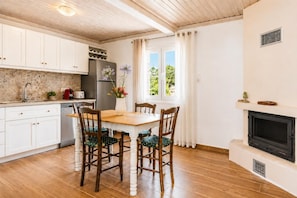 Eine Küche mit Holzschränken, einem Esstisch mit Stühlen, einem Kühlschrank und einem Kamin.