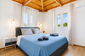 Un dormitorio con cama, mesita de noche y ventana con cortinas.
