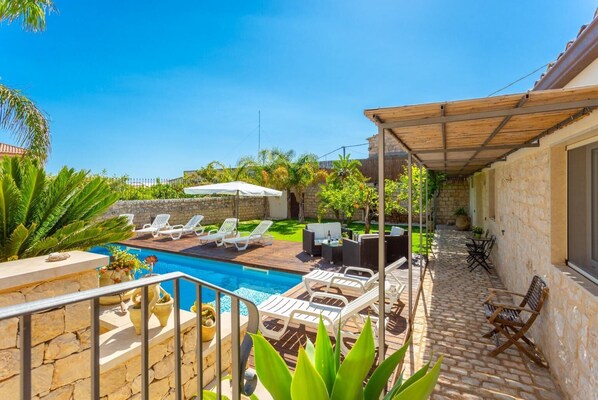 Ein Poolbereich mit Liegestühlen, einem Tisch und einer Pergola.