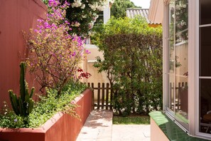 Stroll through a serene courtyard surrounded by lush plants and a simple wooden fence.