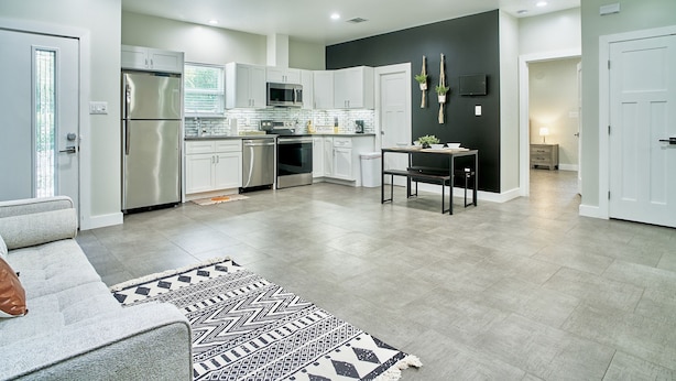 A modern kitchen with white cabinets, stainless steel appliances, and a black accent wall.