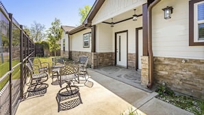 A house with a covered patio area featuring outdoor furniture and a stone pathway.