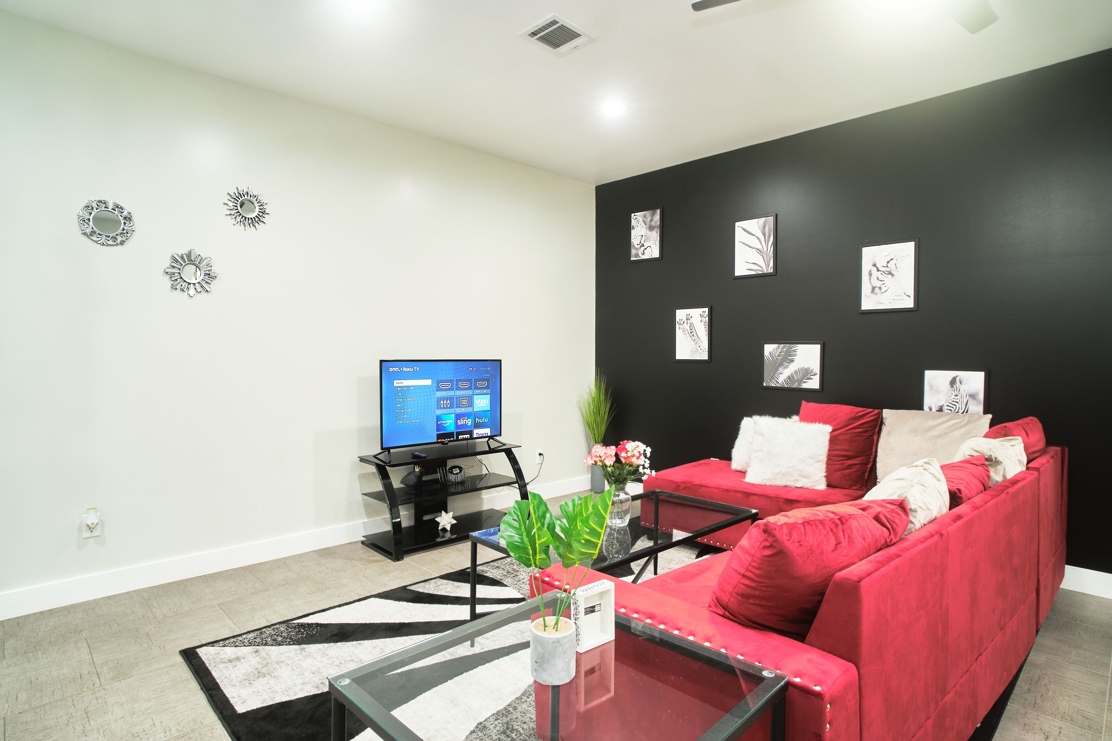 Ein Wohnzimmer mit schwarzer Wand, rotem Sofa und einem Flachbildfernseher.