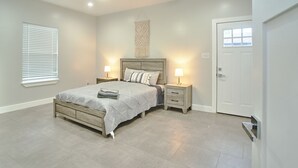 A bedroom with a bed, bedside tables, a ceiling fan, and a door.