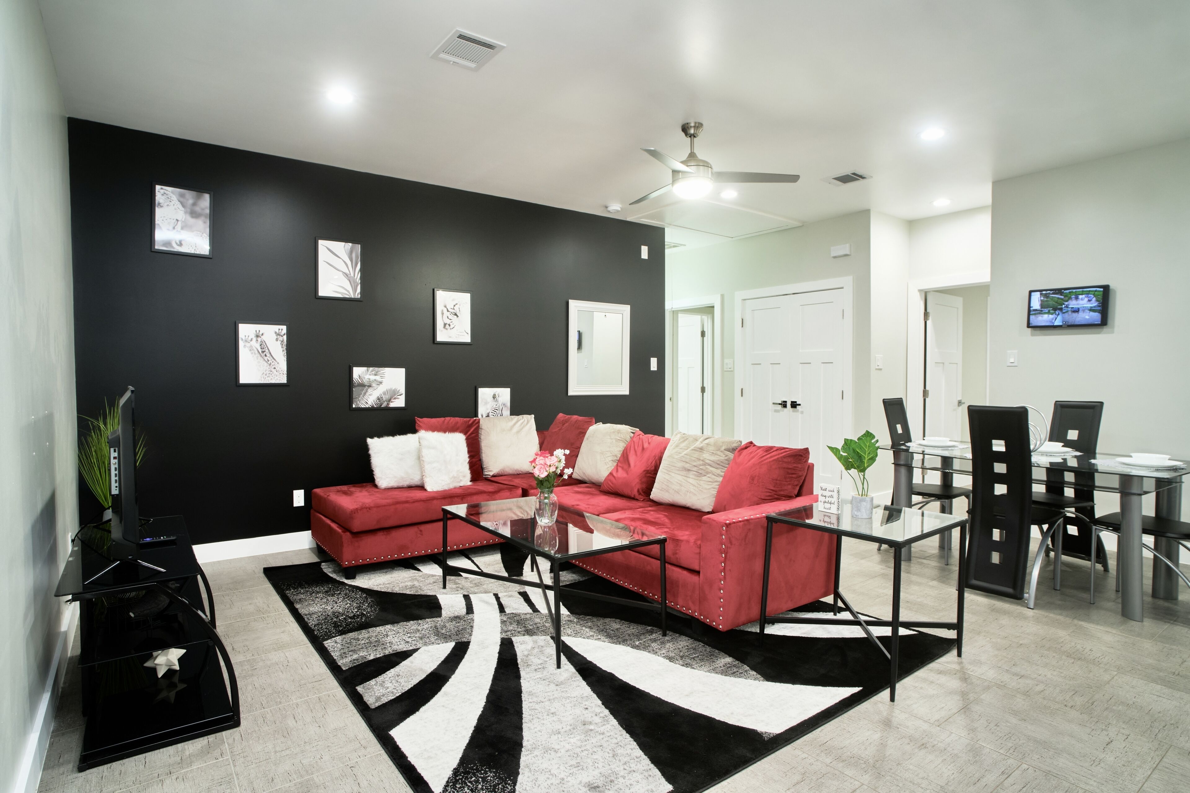 A modern living room with a black and white rug, a red sofa, and a glass coffee table.