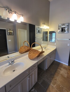 A bathroom with two sinks, a large mirror, and a wicker basket on the countertop.