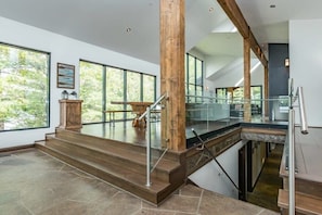 Un intérieur moderne avec un escalier, de grandes fenêtres et une vue sur l’extérieur.