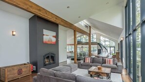 A spacious living area with a fireplace, large gray sofas, and a wooden beam ceiling. - Cherry Island Muskokas Premiere Private Island (Utterson)