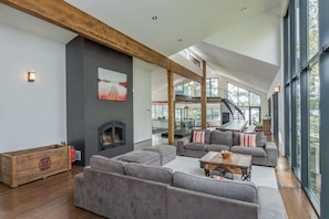 A spacious living area with a fireplace, large gray sofas, and a wooden beam ceiling. - Cherry Island Muskokas Premiere Private Island (Utterson)