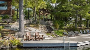 A wooden deck with chairs and a gazebo overlooking a body of water, surrounded by trees. - Cherry Island Muskokas Premiere Private Island (Utterson)