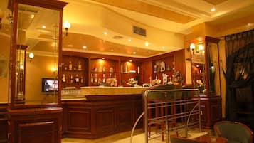 A bar area with wooden cabinets, a counter, and a television screen.