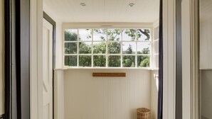 A room with a window, a wicker basket, and a small table with a bowl. - Chic Traditional Highland Estate Cottage with Valley View and Hot Tub (Rothiemay)