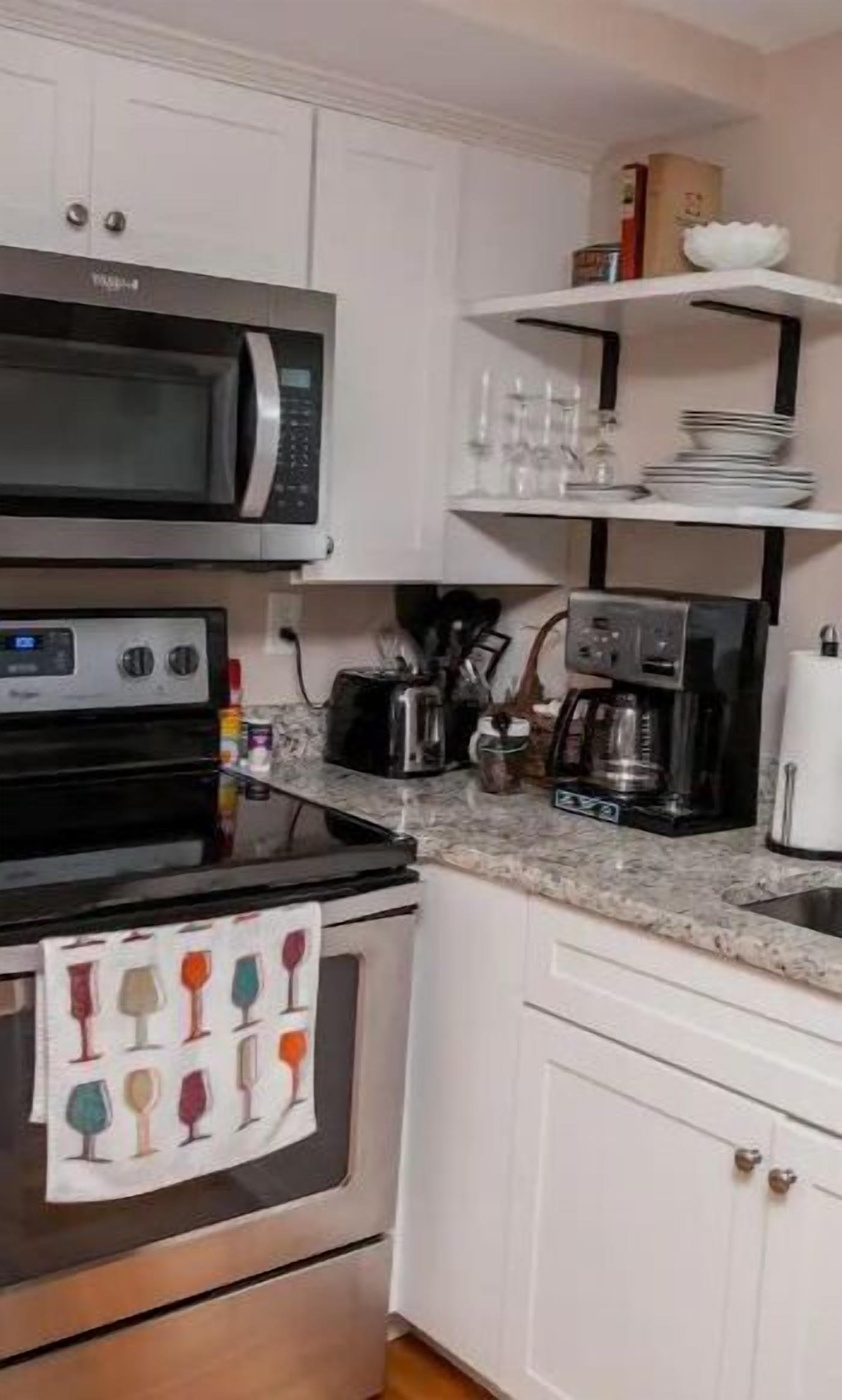 Eine Küche mit weißen Schränken, einer Mikrowelle, einem Toaster, einer Kaffeemaschine und einem Spülbecken.