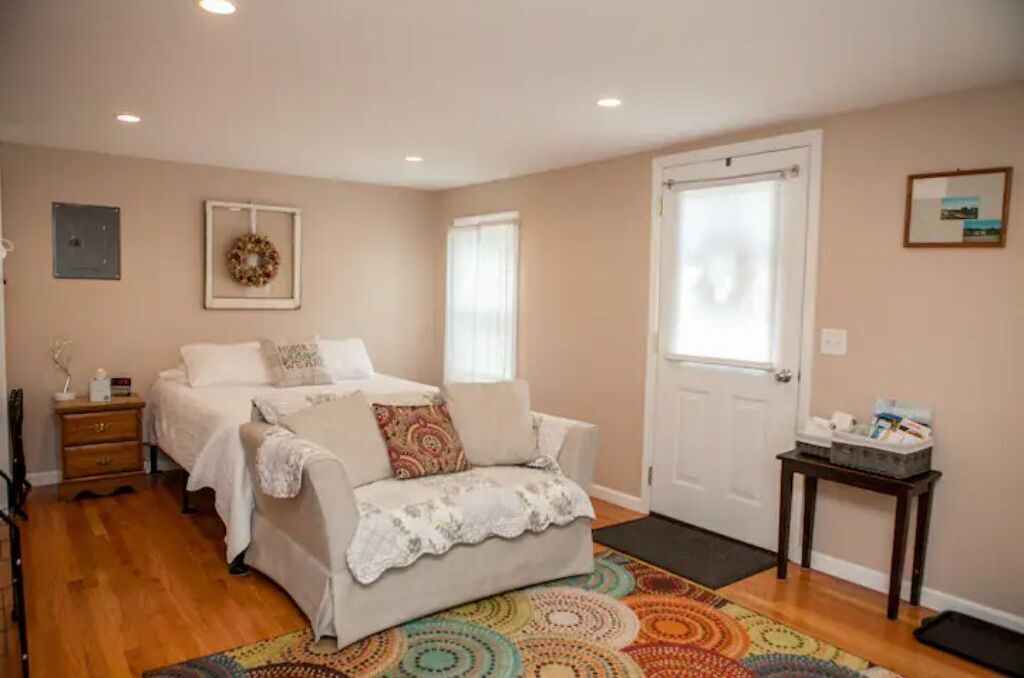 Un dormitorio con dos camas, una mesita, una puerta y una alfombra colorida.