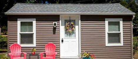 A two-story house with a front porch, two windows, and a door with a wreath.