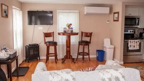 Un espace de vie compact comprenant un coin repas, une kitchenette et un téléviseur fixé au mur.