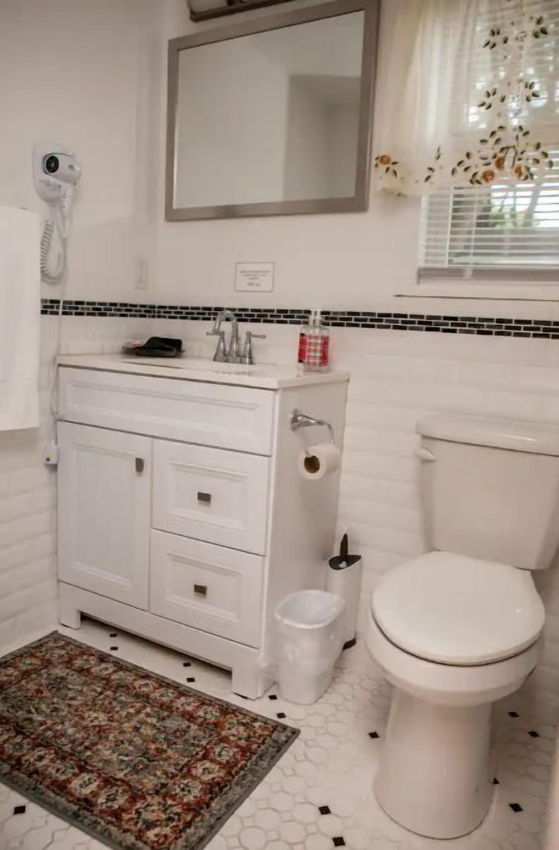 A bathroom with a white vanity, toilet, and a mirror above the sink.
